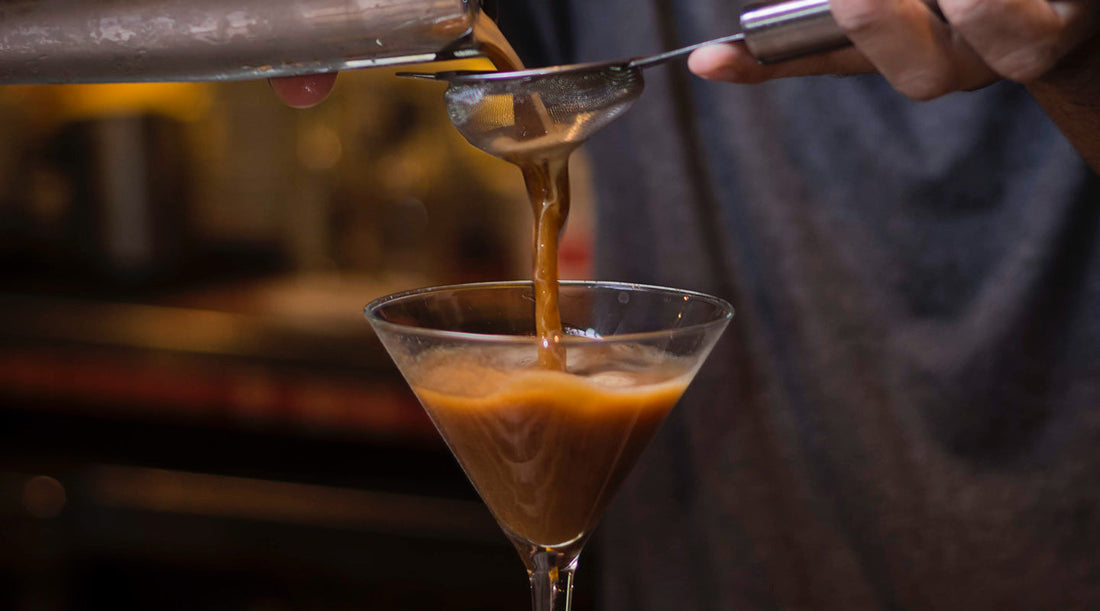 Pouring mixed ingredients into a martini glass.