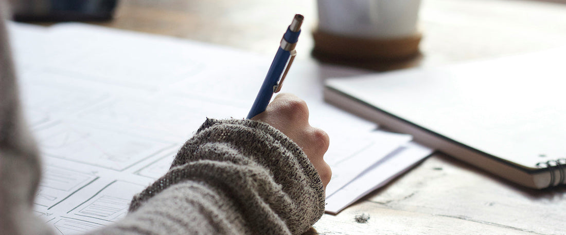 Taking notes in school with a coffee on the desk.