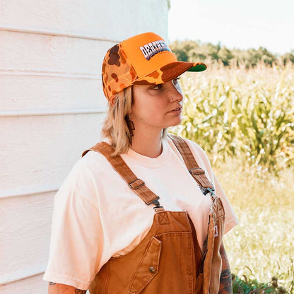 A female model wearing the Death Wish Coffee Hardly Hidden Trucker Hat.