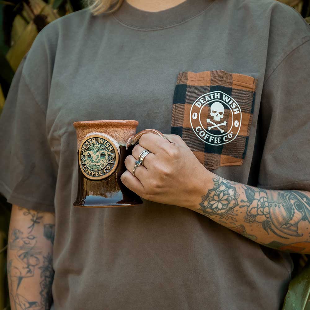 Holding the Death Wish Coffee Scarecrow Mug wearing a matching Patchwork Pocket Tee.