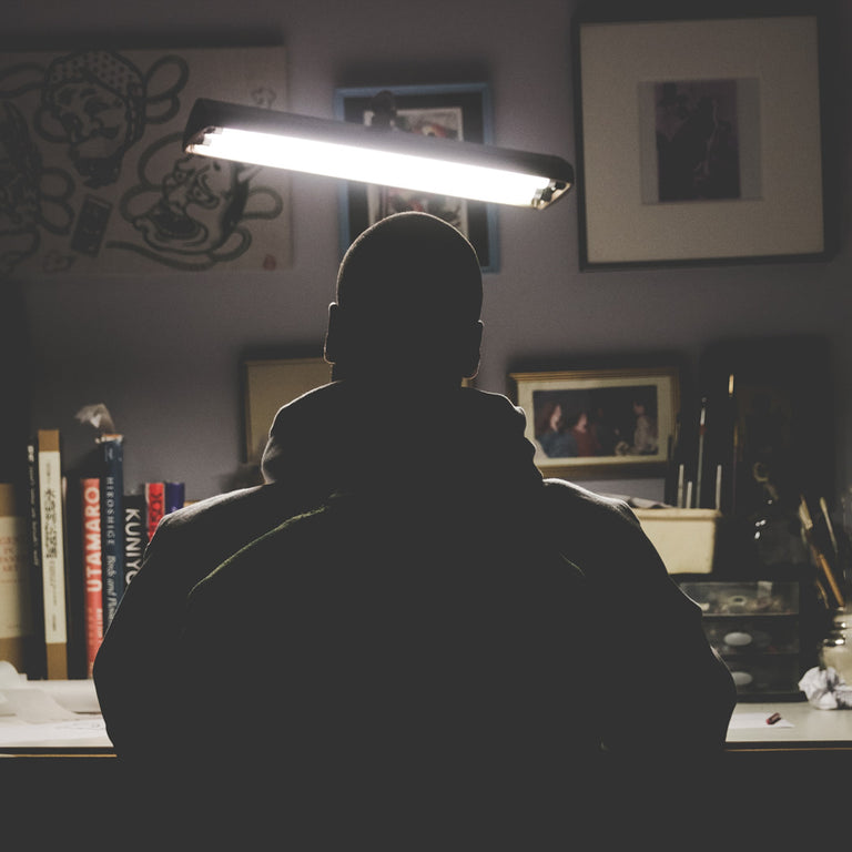 A silhouette of tattoo artist Peter Clarke sitting at a desk.