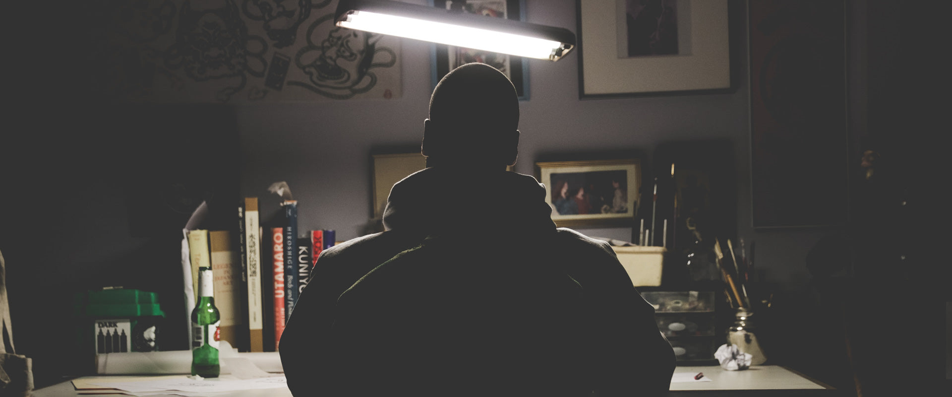 A silhouette of tattoo artist Peter Clarke sitting at a desk.